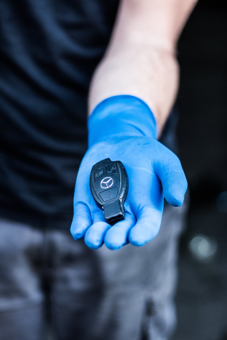 Mano con guante azul sosteniendo la llave de un coche en la entrega tras la ITV